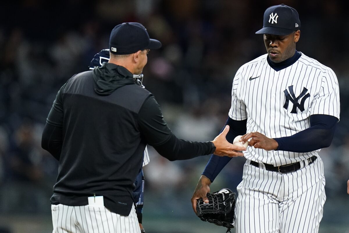 New York Yankees relief pitcher Aroldis Chapman, right, hands the ball to manager Aaron Boone as he leaves during the ninth inning of a baseball game against the Toronto Blue Jays, Thursday, April 14, 2022, in New York. (AP Photo/Frank Franklin II)