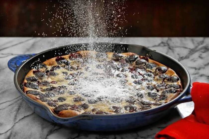 Powdered sugar is sprinkled atop a fresh cherry clafoutis.