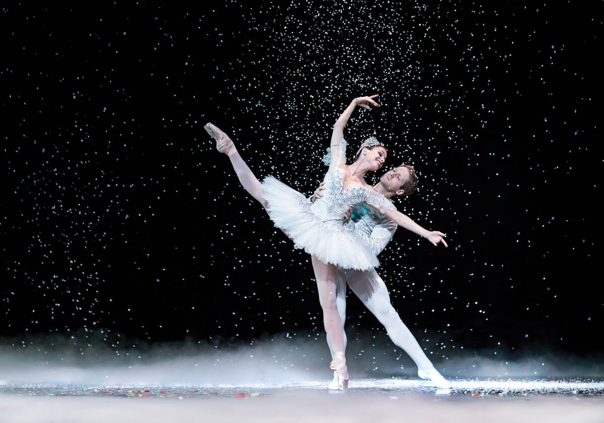Male and female ballet dancers performing under stage snow