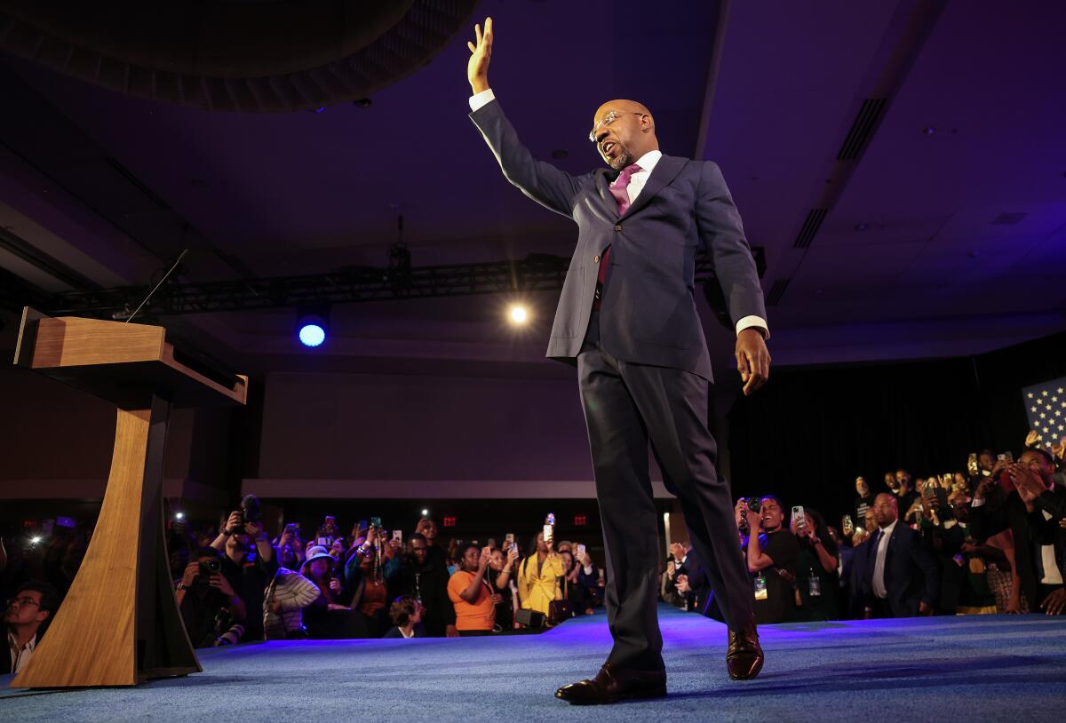 Sen. Raphael Warnock (D-Ga.) waves to the crowd from a stage.