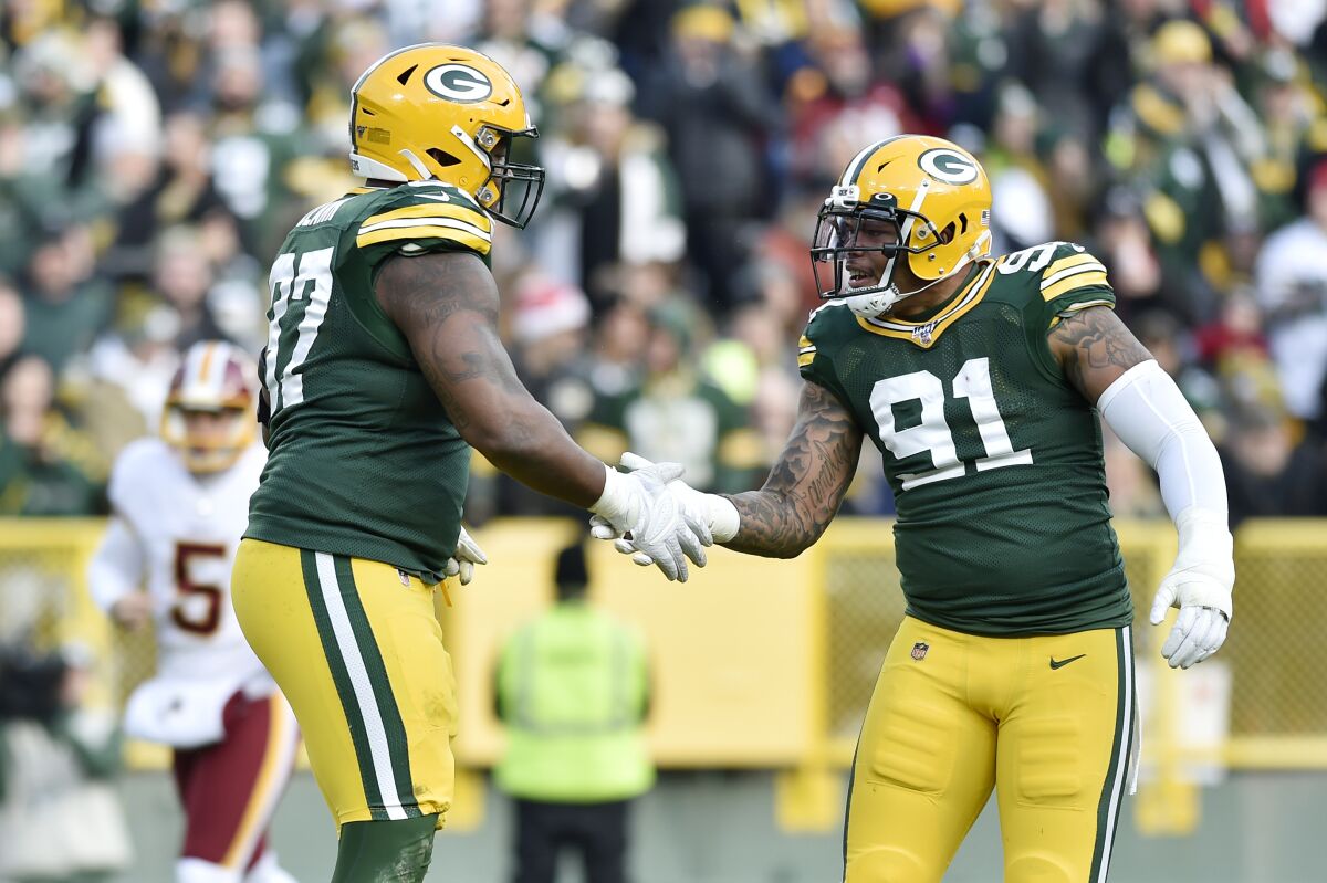 Green Bay Packers' Preston Smith (91) congratulates teammate Kenny Clark (97) for his sack in the second half against the Washington Redskins on Dec. 8 in Green Bay, Wisc.