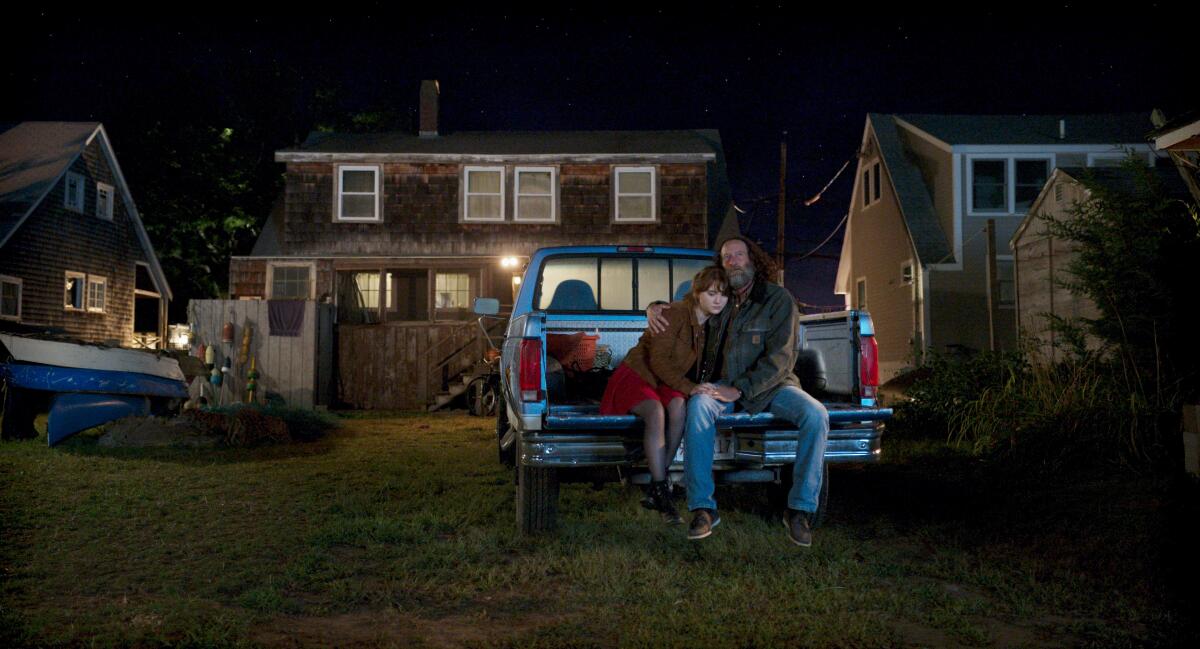 Emilia Jones and Troy Kotsur sit on the tailgate of a pickup in a scene from “CODA.”