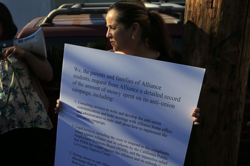 Maria Esparza of Huntington Park, shown outside Alliance Gertz-Ressler Academy High School in Los Angeles last November, holds up a sign detailing parents' concerns about Alliance's handling of unionization efforts.