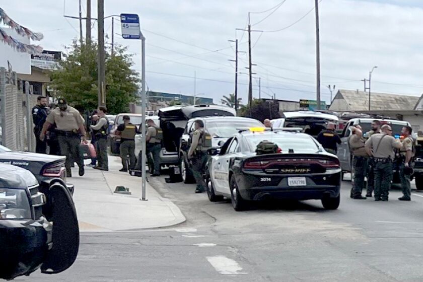 The Monterey County Sheriff's Department deputies and vehicles stand scattered on a corner of two streets.