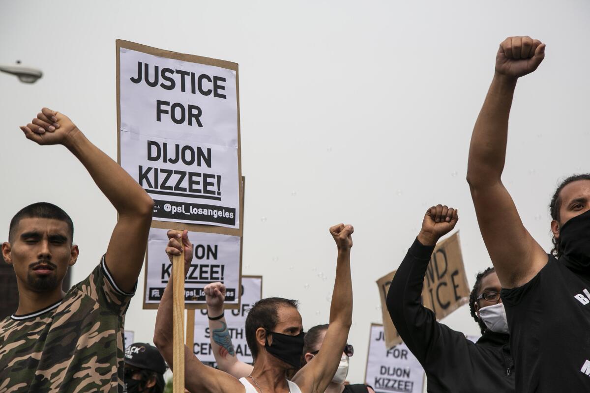 Protesters raise their fists as they march down Vermont Avenue holding signs demanding justice for Dijon Kizzee