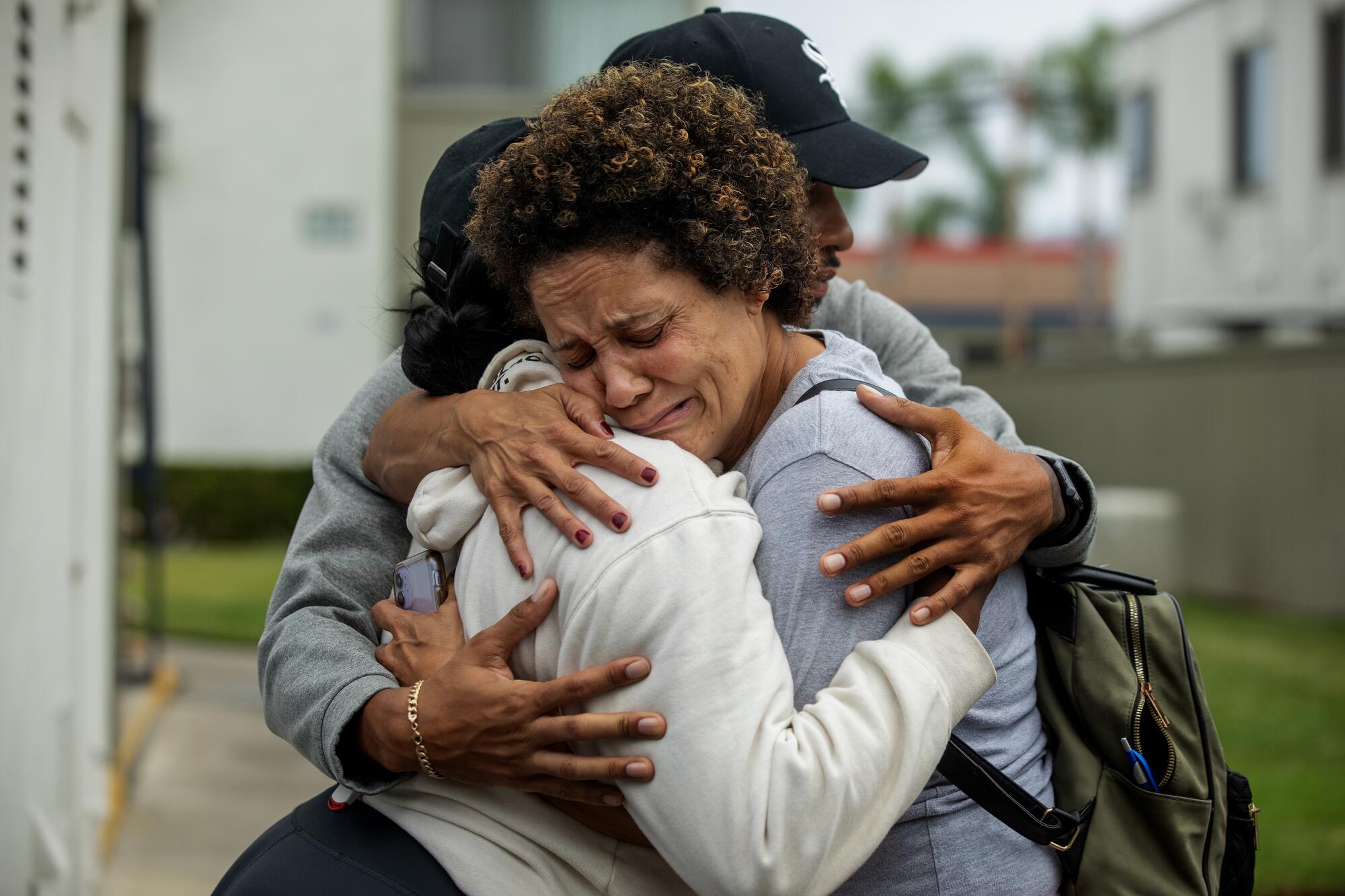 Christine LyBurtus is comforted by Schahara Zad, left, and Terrence Morris, caregivers for her son Noah