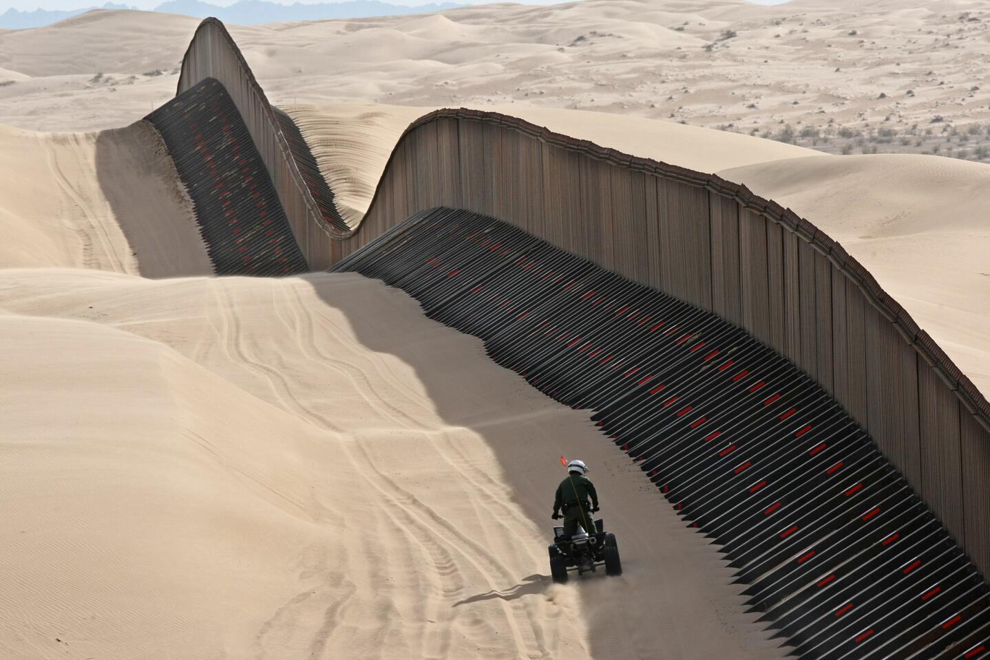 March 4, 2009: A U.S. Border Patrol agent inspects the "floating fence" that sits atop the powdery Imperial Sand Dunes in California. Angled buttresses on either side give the fence stability atop the wind-blown sand.
