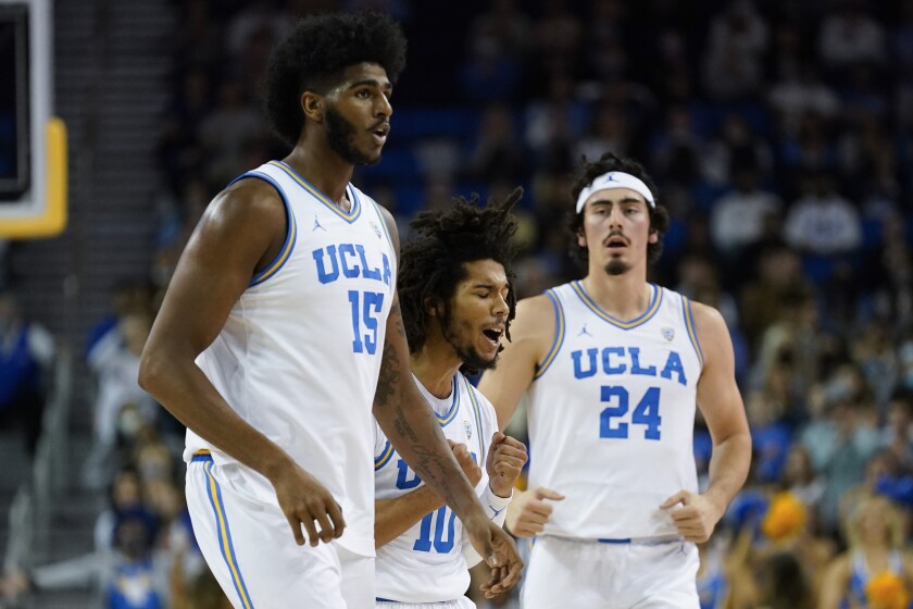 UCLA guard Tyger Campbell (10) celebrates with center Myles Johnson (15) and guard Jaime Jaquez Jr. (24) after scoring during the first half of an NCAA college basketball game against the Colorado in Los Angeles, Wednesday, Dec. 1, 2021. (AP Photo/Ashley Landis)