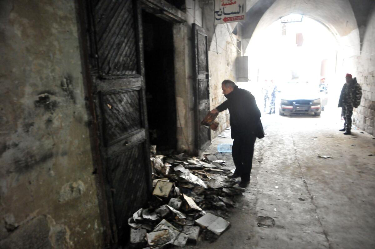 A man inspects burned books after an arson fire at the Saeh Library in Tripoli, Lebanon.