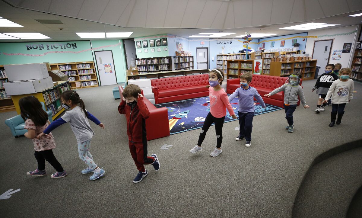Kindergarteners practice social distance walking through the library at Lupin Hill Elementary School.