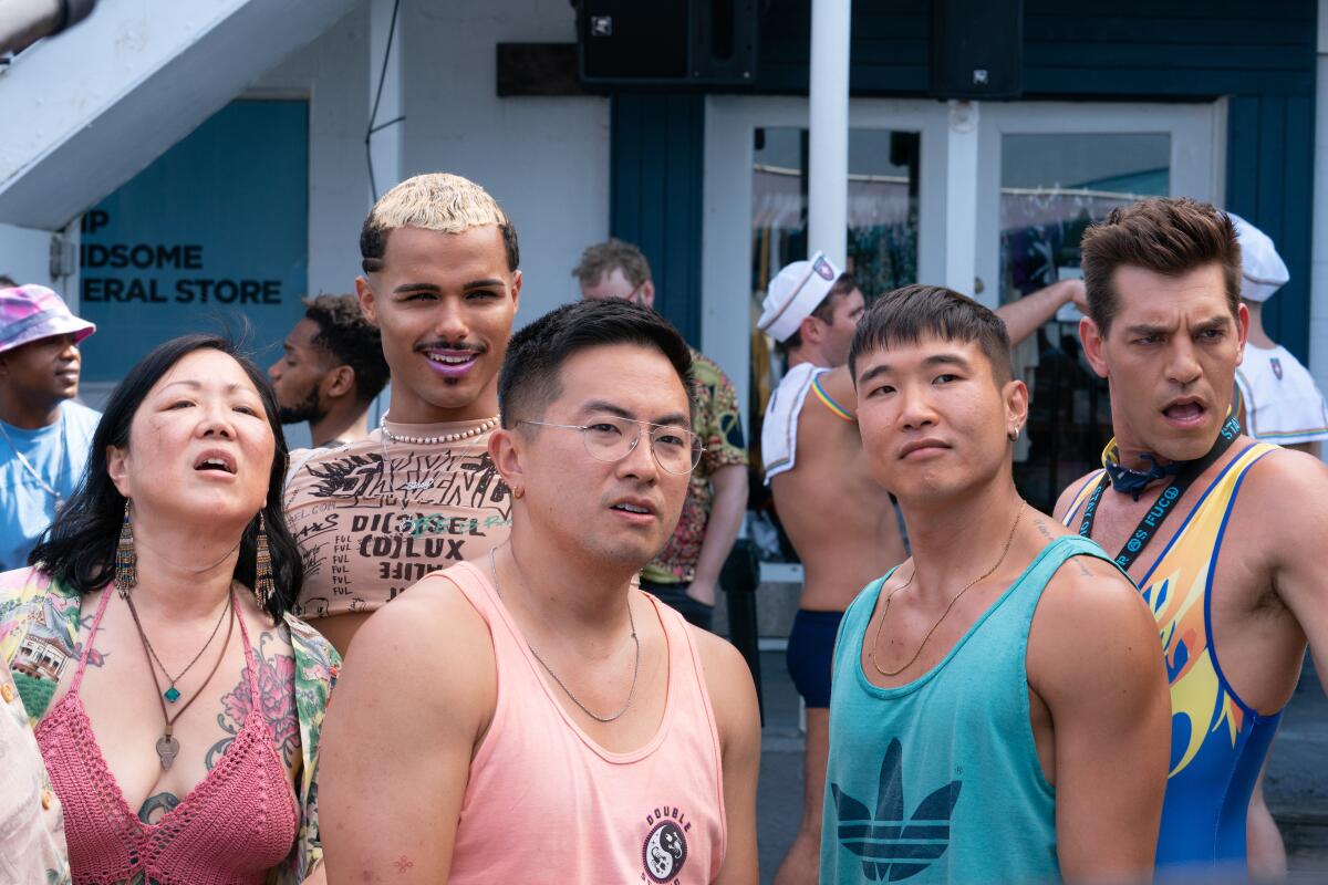 Five people in summer tank tops stand together outside a store looking off-camera.