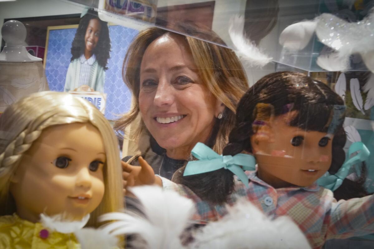 Jamie Cygielman, general manager and president at American Girl, poses behind a showcase of dolls during a press tour.