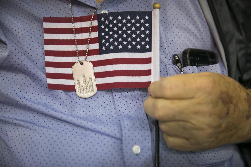 Hans Gottwald clutches a small American flag under his military dog tags while he waits for his naturalization ceremony to begin at the M.O. Campbell Education Center on Saturday, Sept. 18, 2019, in north Houston. Gottwald decided to become naturalized after 56 years in the United States to pursue the right to vote in upcoming elections.