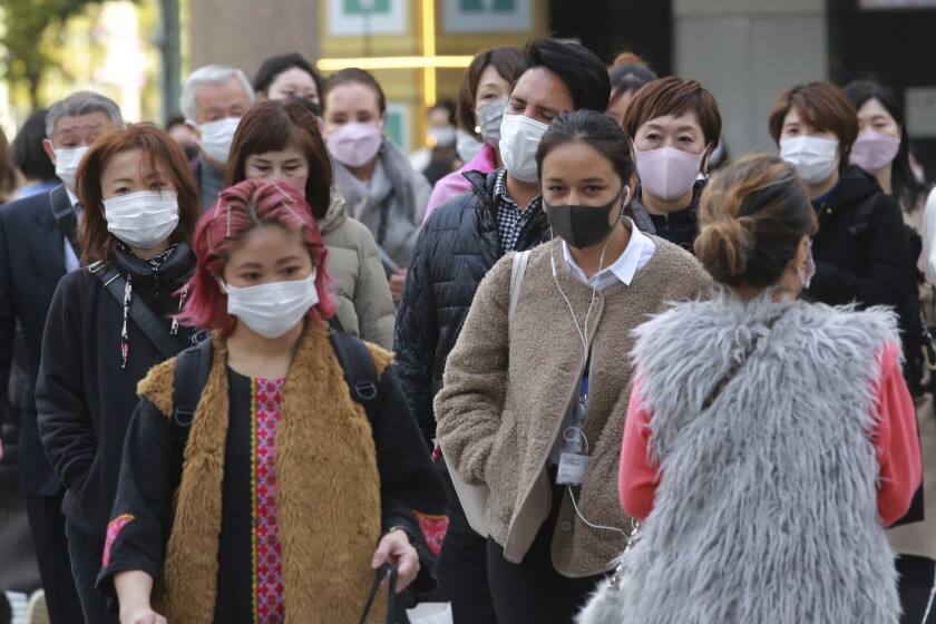 Transeúntes, con mascarilla para protegerse del coronavirus, caminan por una calle en Tokio