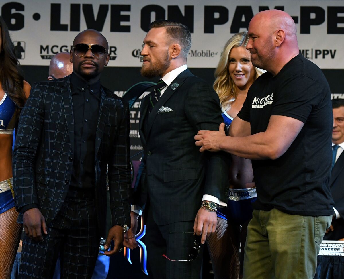 Floyd Mayweather Jr., left, poses as UFC President Dana White pulls back on Conor McGregor during a news conference on Aug. 23.