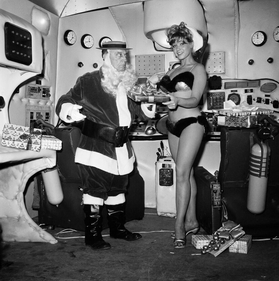 Buster Keaton, comic film actor from the silent era, dressed as Santa Claus, and Bobbi Shaw as Santa's helper are on the set of "Beach Blanket Bingo" in Los Angeles on Dec. 17, 1964.