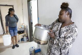 LOS ANGELES, CA - JULY 05: Daviell McKinley, left, and Charlotte Arnold are among residents who use buckets and pots for heating and collecting hot water on the kitchen stove. Tenants at 5700 S. Hoover Street are living in squalid and dangerous apartments. They don't have hot water, there is mold, rats and trash problems. They haven't heard anything from city officials following their visit months ago. Photographed on Friday, July 5, 2024 at 5700 S. Hoover Street in Los Angeles, CA. (Myung J. Chun / Los Angeles Times)