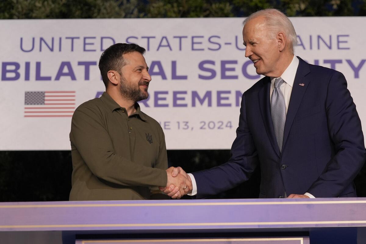 President Biden and Ukrainian President Volodymyr Zelensky shake hands.