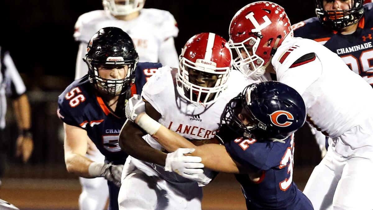 Orange Lutheran's Reginald Strong Jr. tries to break through a tackle by Chaminade's Blake Antzoulatos during their playoff game Friday night.