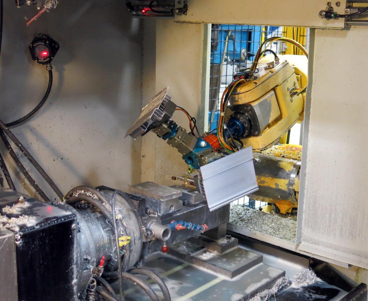 A robot loads a part into a milling machine at Alexandria Industries in Alexandria, Minn., on April 9. Skilled workers no longer need to load the machine.