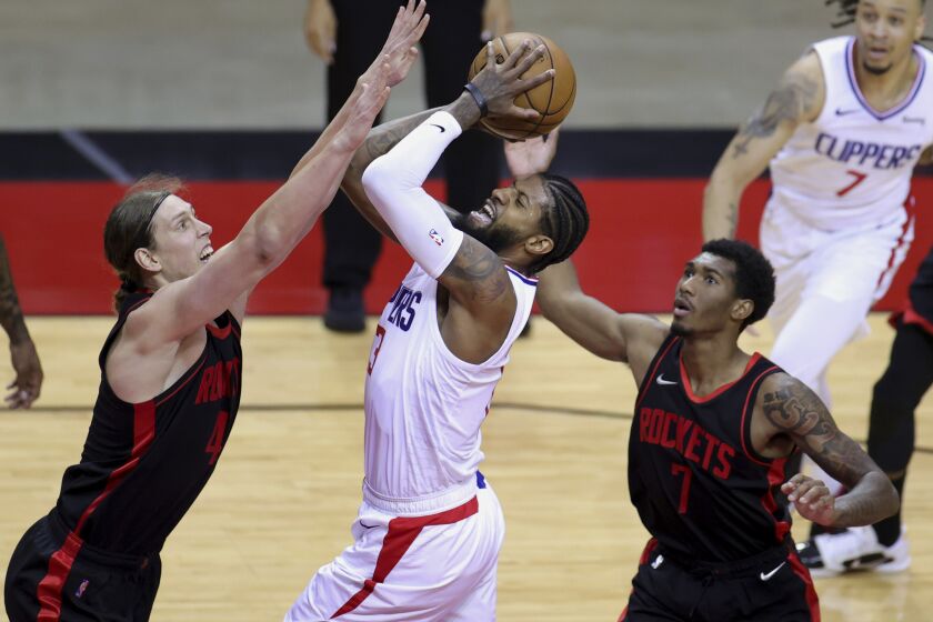 Los Angeles Clippers' Paul George looks to shoot against Houston Rockets' Kelly Olynyk (41) and Armoni Brooks.
