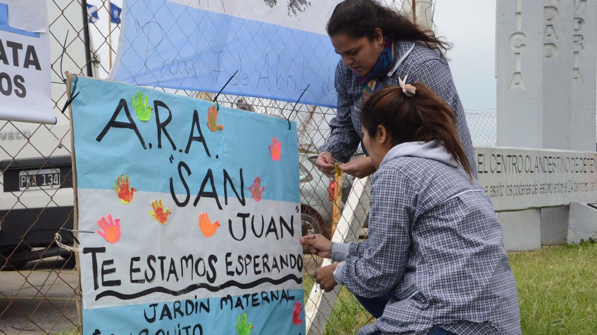 Schoolteachers hang a sign with the colors of the Argentine flag that reads in Spanish "ARA San Juan, we wait for you" on a the fence at the naval base in Mar del Plata on Nov. 20, 2017.