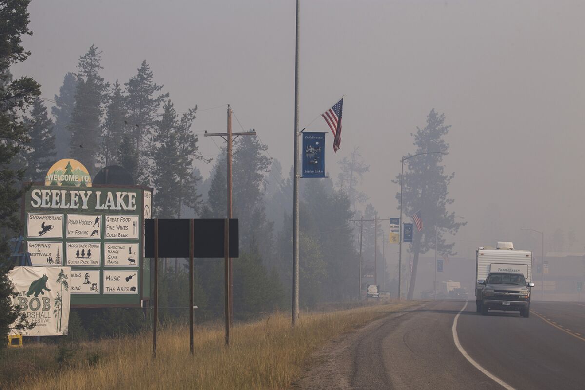 A pickup truck pulls a camper through the wildfire smoke in Seeley Lake, Mont., during the 2017 fire season.
