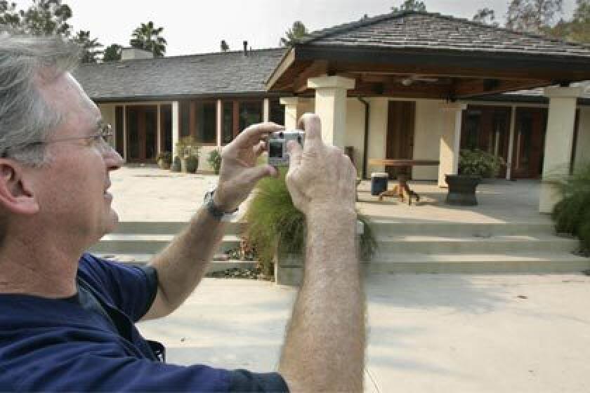 SURVIVOR: Dr. David Roland takes a snapshot of his house in Rancho Santa Fe, Calif., which had been sprayed with fire retardant by a private firm and emerged from the flames intact.