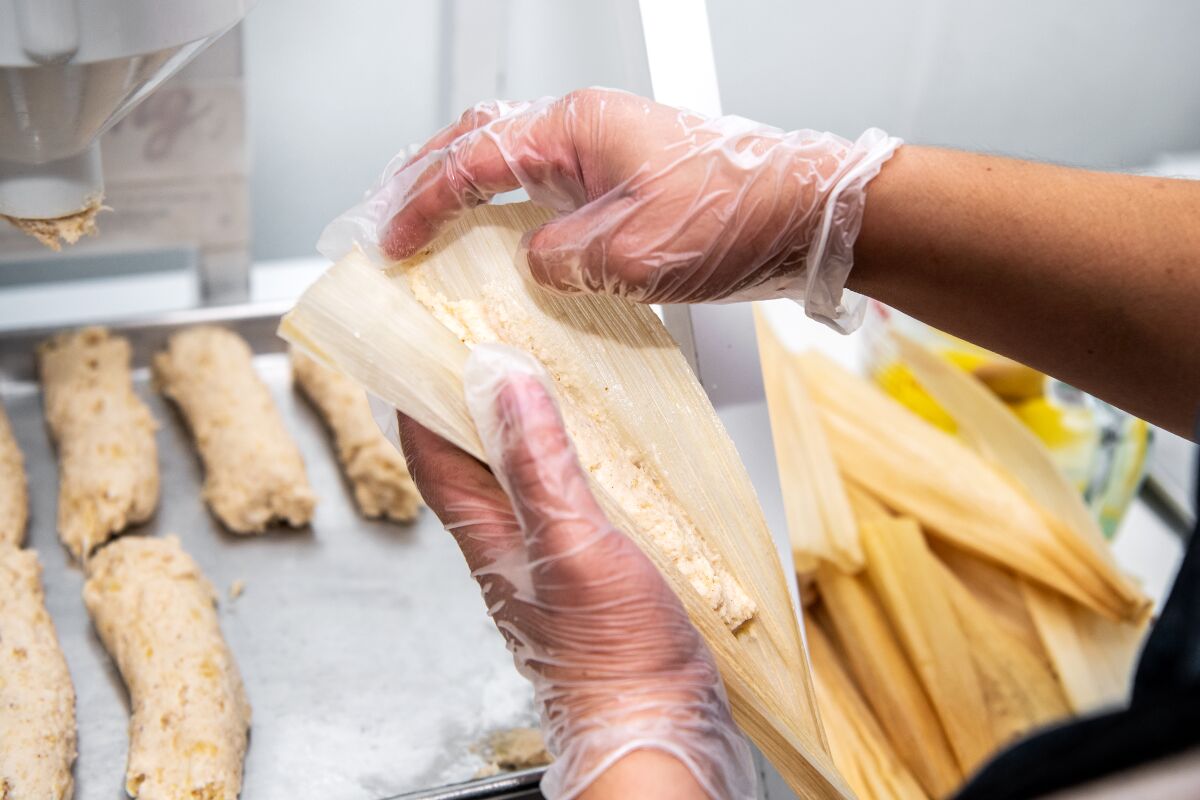 Vanessa Rodriquez constructs tamales at Artesano Tamaleria. The restaurant uses a machine that quickly and more accurately dispenses the masa, which traditionally is done by hand, saving them time.