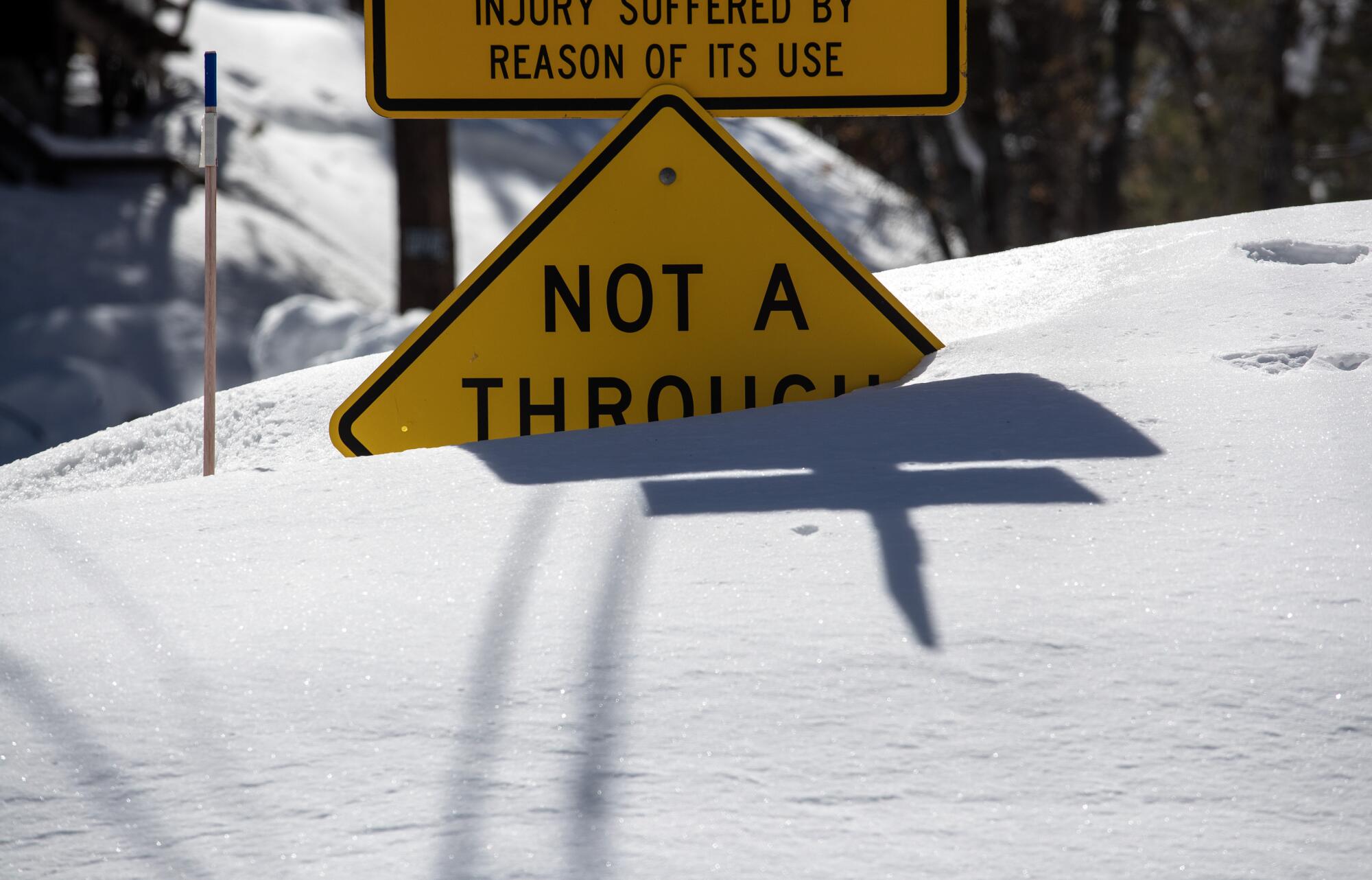 A street sign is nearly covered by snow.