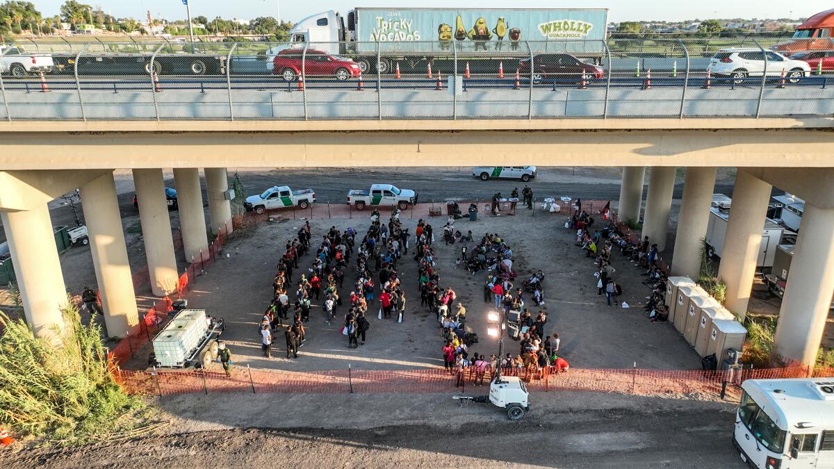 People who crossed the U.S.-Mexico border are held at a border patrol processing center under a bridge.