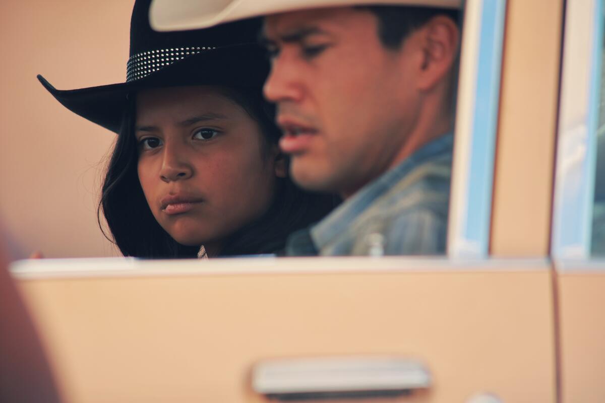 Two people in cowboy hats in a car.