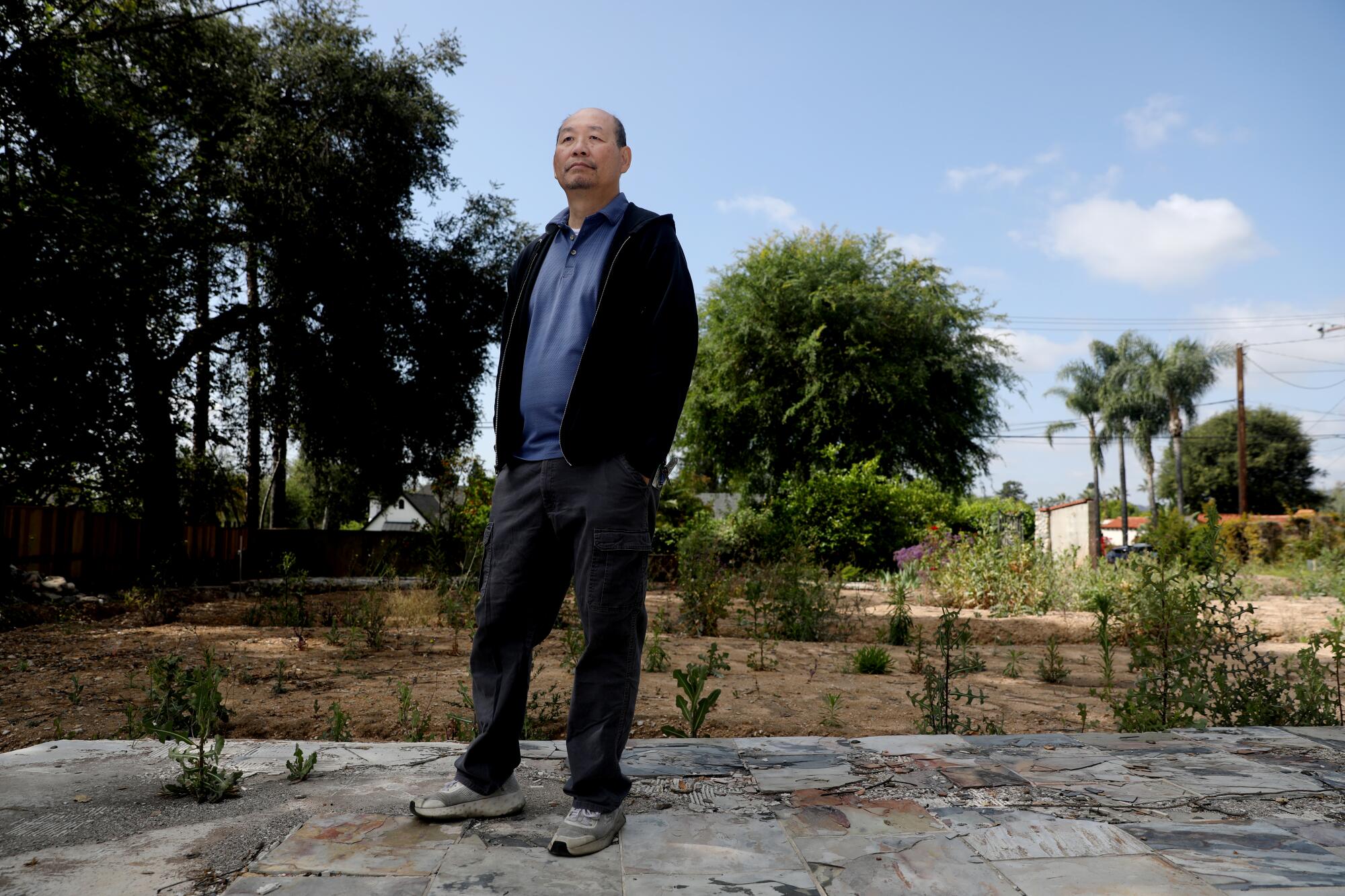 A man stands on an empty home lot in Altadena.
