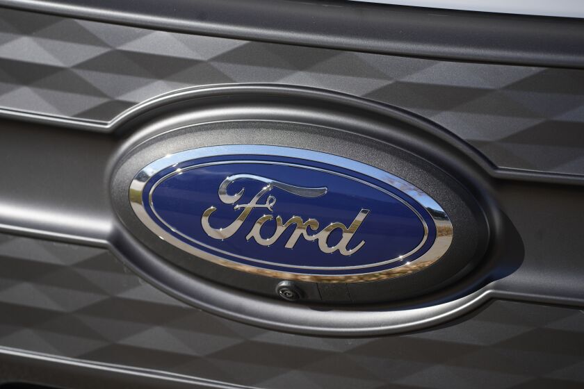 FILE - Company logo shines off the grille of an unsold 2023 F-150 Lightning pickup truck Thursday, Nov. 25, 2022, outside a Ford dealership in southeast Denver. Ford is recalling nearly 383,000 SUVs in the U.S. because the touch screens may not display a camera image when backing up. The recall covers certain 2020 to 2023 Ford Explorers and Lincoln Aviators, and some 2020 to 2022 Lincoln Corsairs. (AP Photo/David Zalubowski)