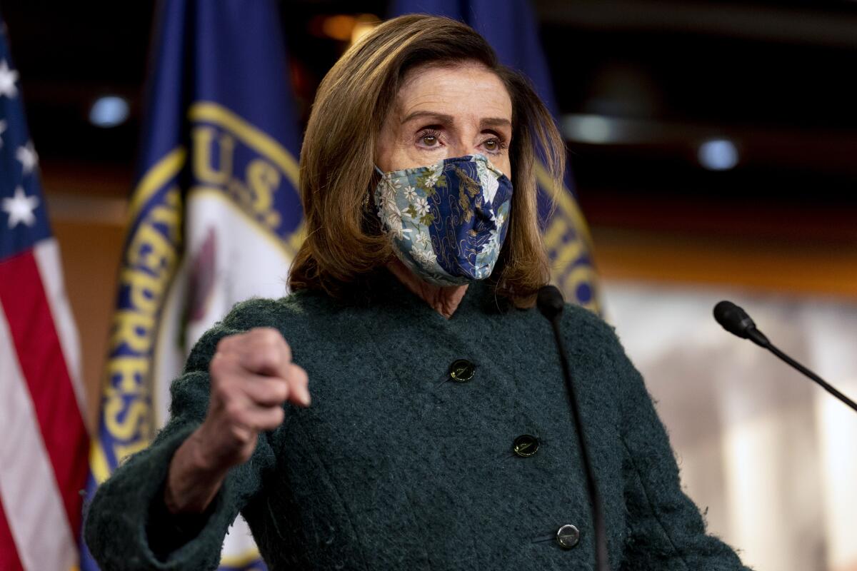Nancy Pelosi, wearing a mask, speaks into a microphone