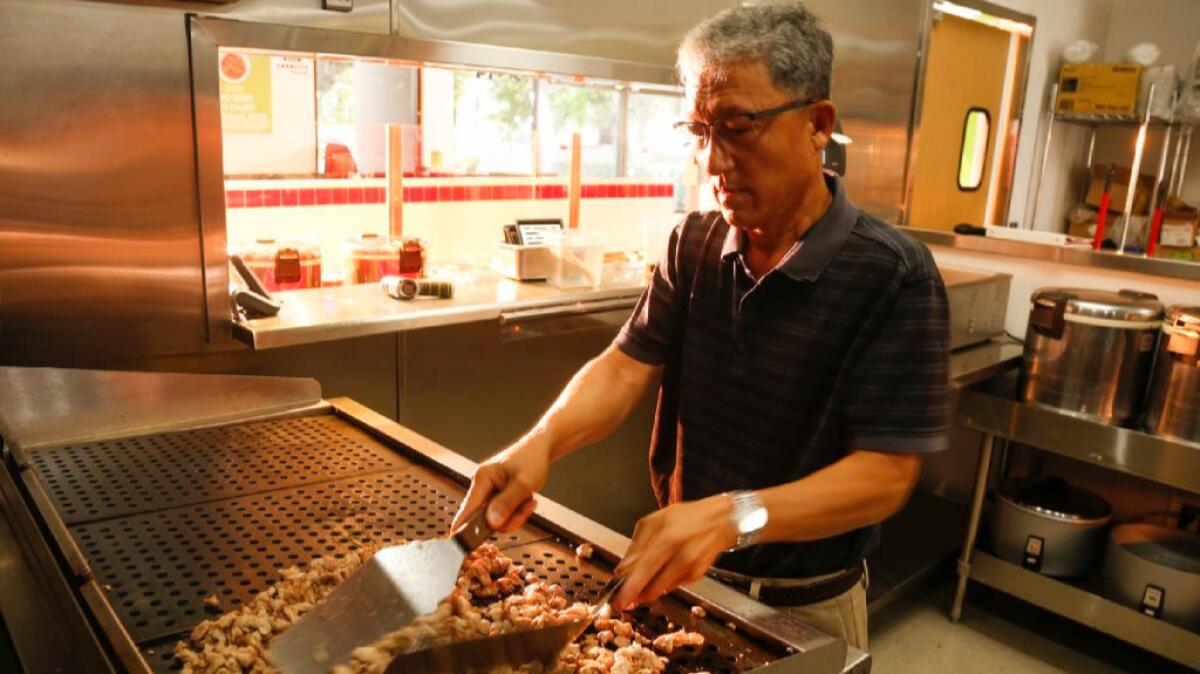 Young R. Lee, chief executive of Flame Broiler Inc., still takes time out of his busy day to grill chicken and work in the kitchen at the company restaurant in Santa Ana.