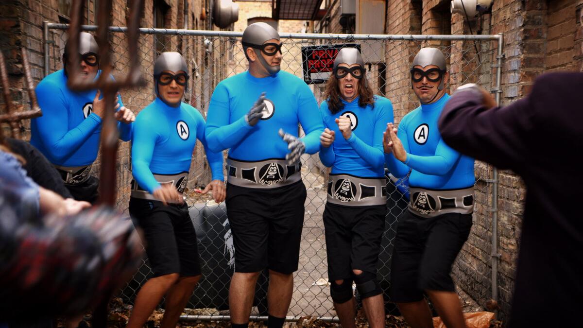 A group of middle age adults in cheap-looking matching superhero costumes.