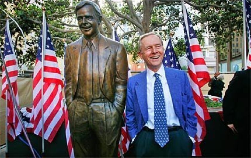 Pete Wilson stands by his bronze statue in downtown San Diego.