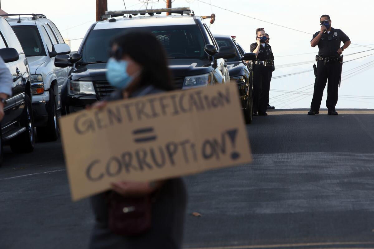 Protester holds a sign reading, "Gentrification = corruption" 