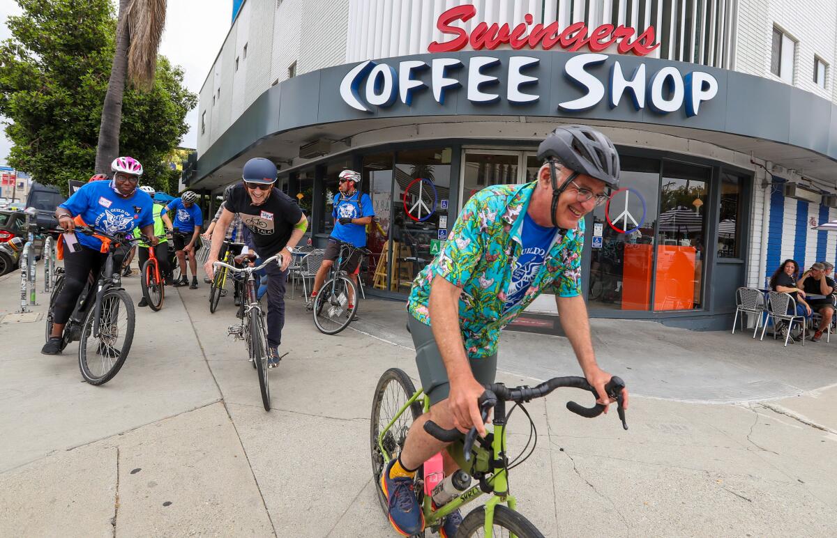 Shem Bitterman, in a Hawaiian shirt over his blue WGA tee, hops on his bike with a group tailing behind at Swingers Diner.