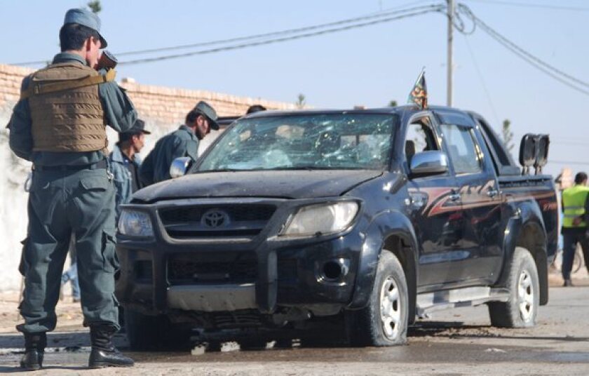 Afghan police on Sunday inspect the vehicle of Mohammed Tahir Wadat, deputy governor of Balkh province, at the scene of a suicide bomb attack.