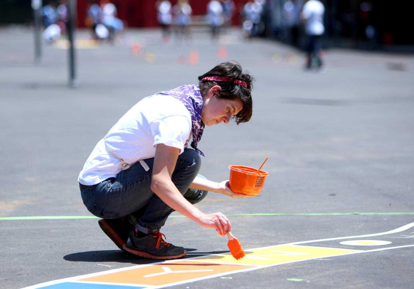 Disney employees like Kat Reilly shown painting an alphabet hop-scotch, helped improve the playground at Mann Elementary School in Glendale on Thursday, July 14, 2016. Kaboom, Disney and Glendale Educational Foundation got together to build a playground at the school and improve the campus.