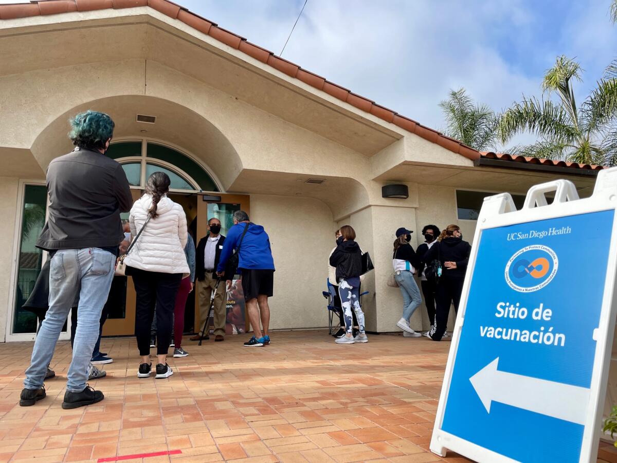 People at a vaccination site with a sign reading "Sitio de vacunación"