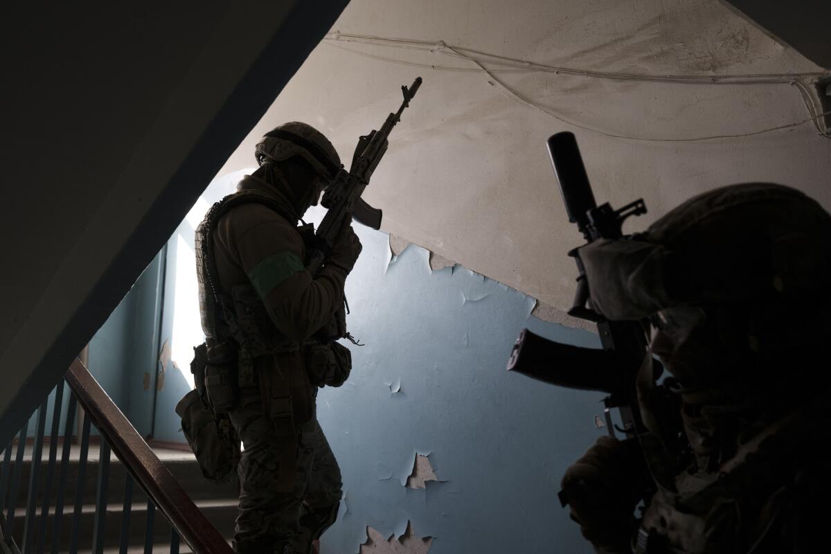 Men in military gear hold guns inside a building