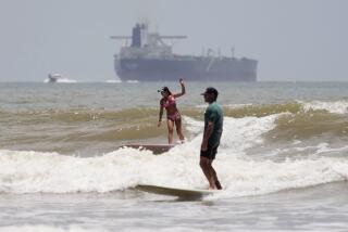 An oil taker heads out to open water as surfers take advantage of waves ahead of Hurricane Beryl's arrival in Port Aransas, Texas, Saturday, July 6, 2024. (AP Photo/Eric Gay)