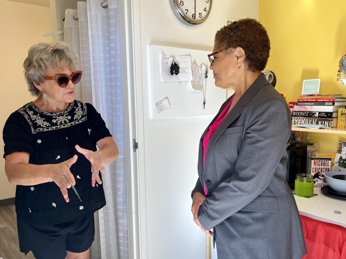 Mayoral candidate Karen Bass, right, listens to the resident of a new home made from a repurposed cargo container.