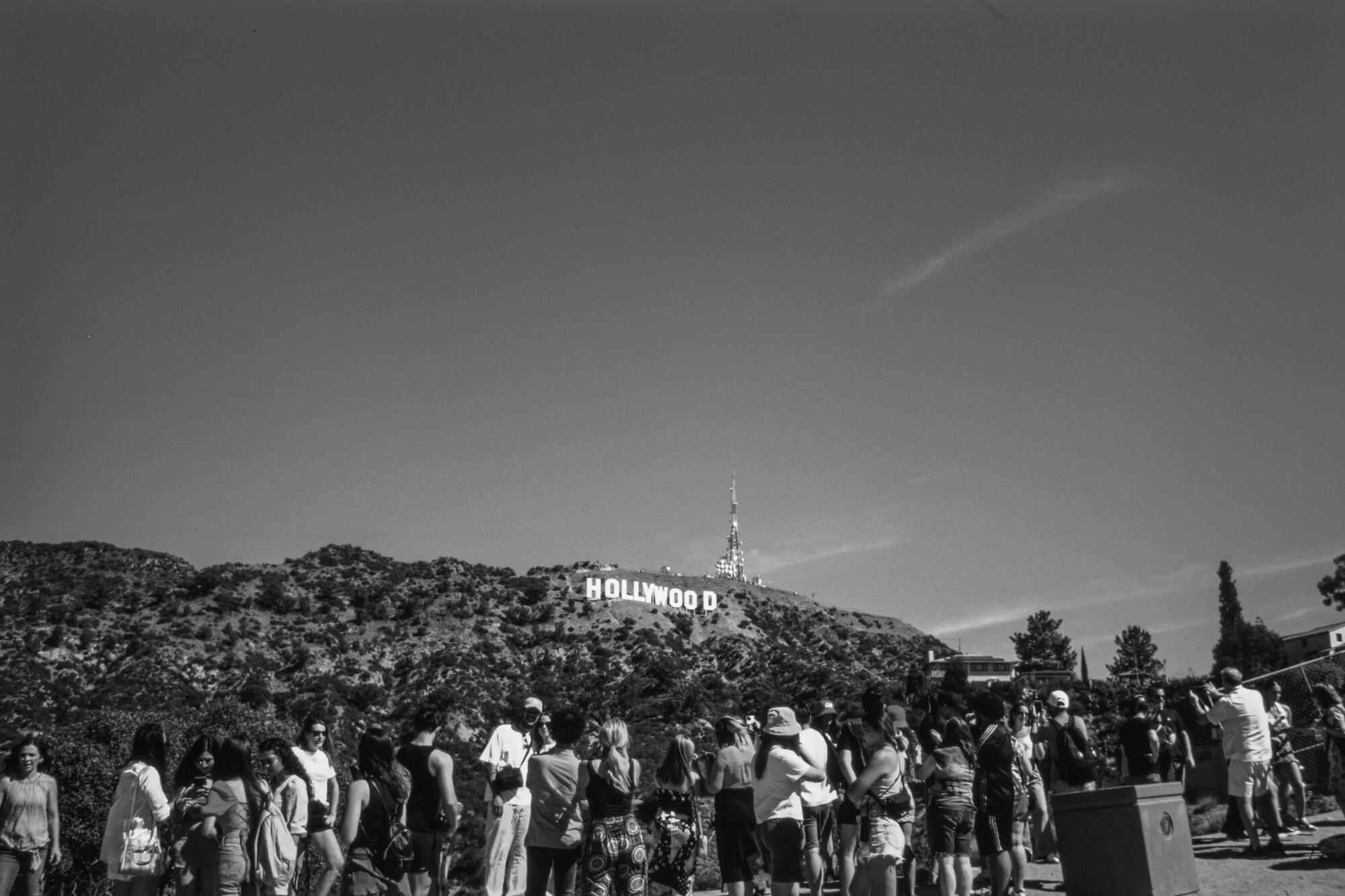 A crowd of tourists gathering to take photos of the Hollywood sign