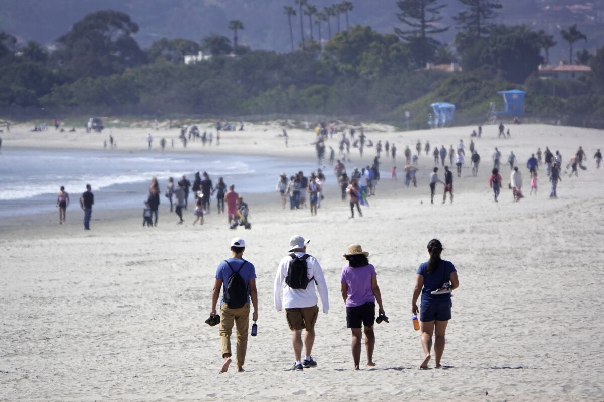 People walk along the beach in Coronado