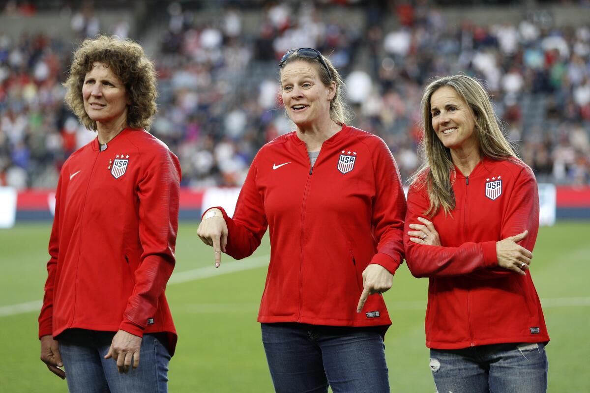 U.S. Soccer president Cindy Parlow Cone stands between U.S. soccer legends Michelle Akers, left, and Brandi Chastain.