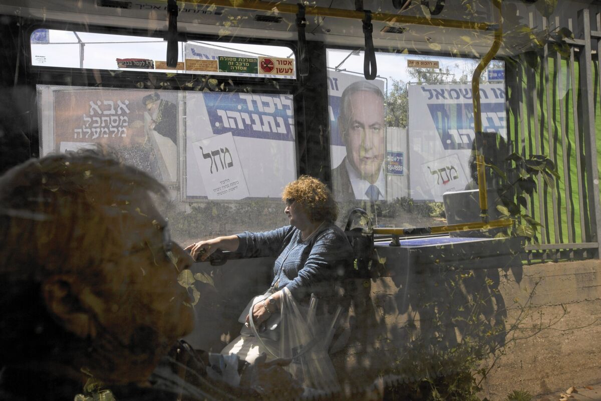 A bus passes a billboard featuring Israeli Prime Minister Benjamin Netanyahu, right, near Tel Aviv last week. He said he did not intend to offend in warning that Arab voters were heading to the polls “in droves.”